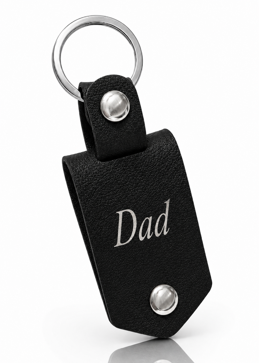 A black textured leather keychain with a silver metal key ring, two silver snap buttons, and the word 'Dad' engraved in silver on the front, shown on a white background with a soft reflection.