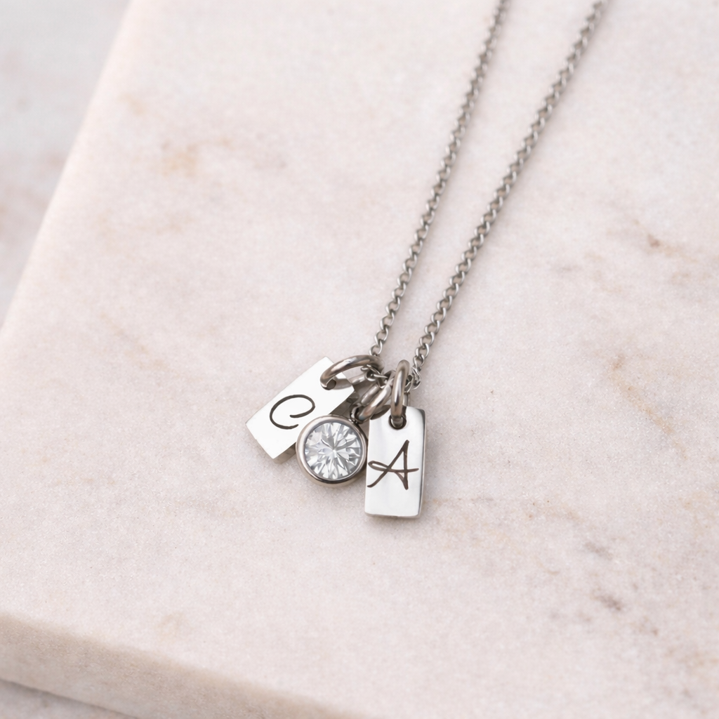 Silver necklace with three charms on a marble surface