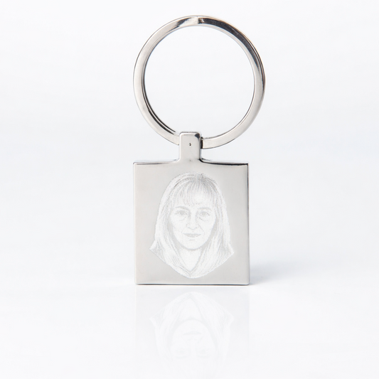 Silver keychain with a face design on a white background