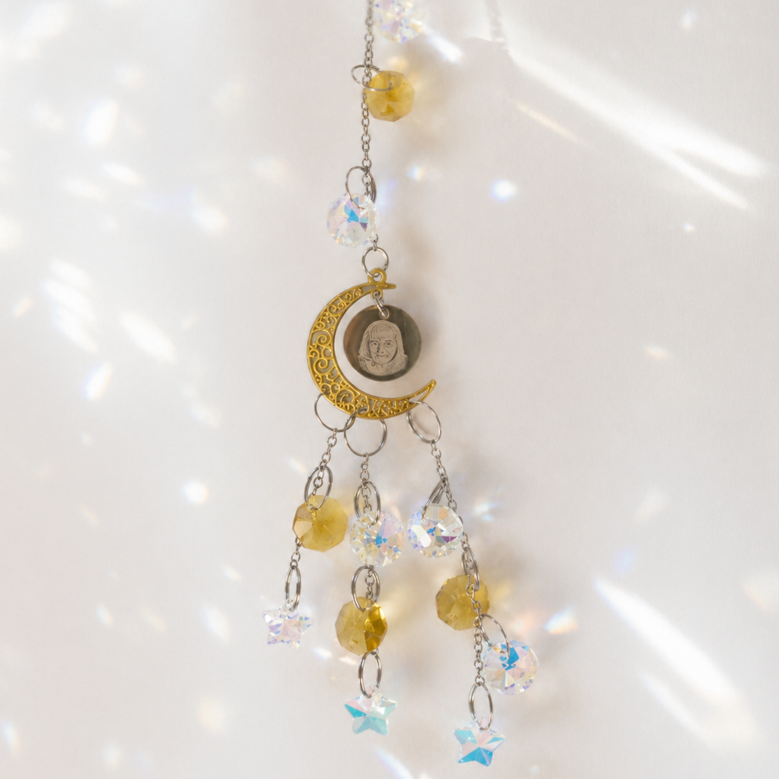 Decorative hanging charm with crystals and a moon design on a white background