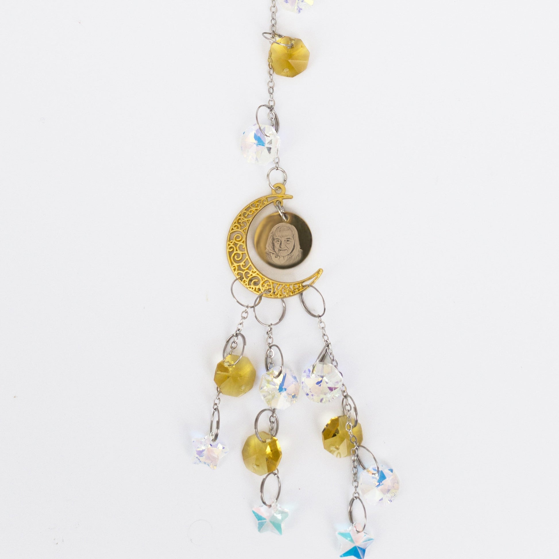 Decorative engraved hanging charm with yellow beads and a moon symbol on a white background