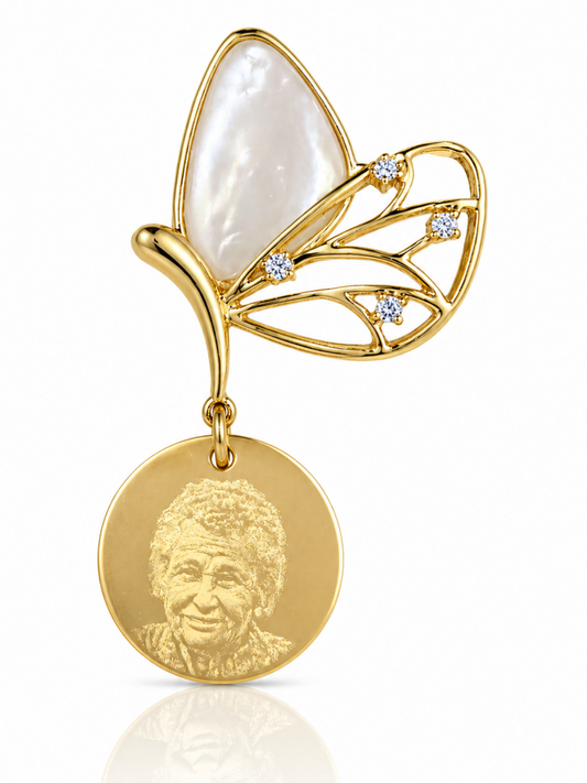 Gold butterfly pendant with a circular medallion featuring a portrait on a white background