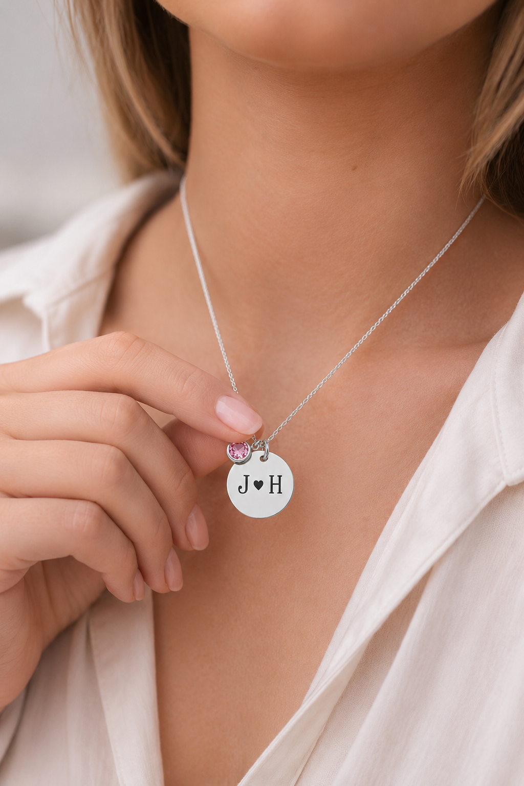 Necklace with circular pendant and heart charm worn by a person