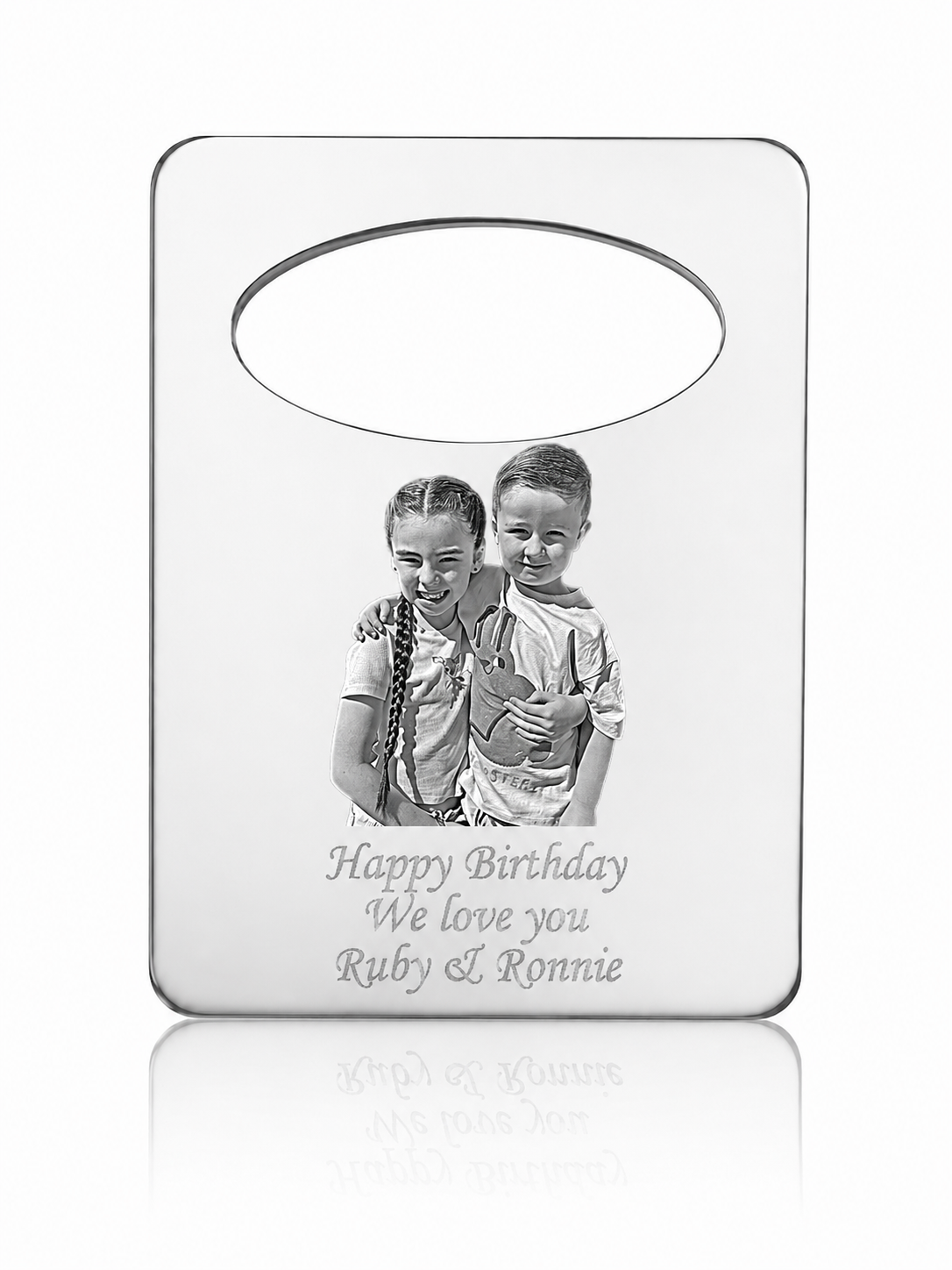 A personalized silver-toned metal keepsake plaque with a photo of two children and the engraved text 'Happy Birthday We love you Ruby & Ronnie', shown on a clean white background with a soft reflection below.