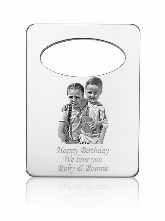 A personalized silver-toned metal keepsake plaque with a photo of two children and the engraved text 'Happy Birthday We love you Ruby & Ronnie', shown on a clean white background with a soft reflection below.