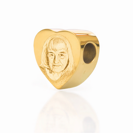 Gold heart-shaped charm with a face on a white background