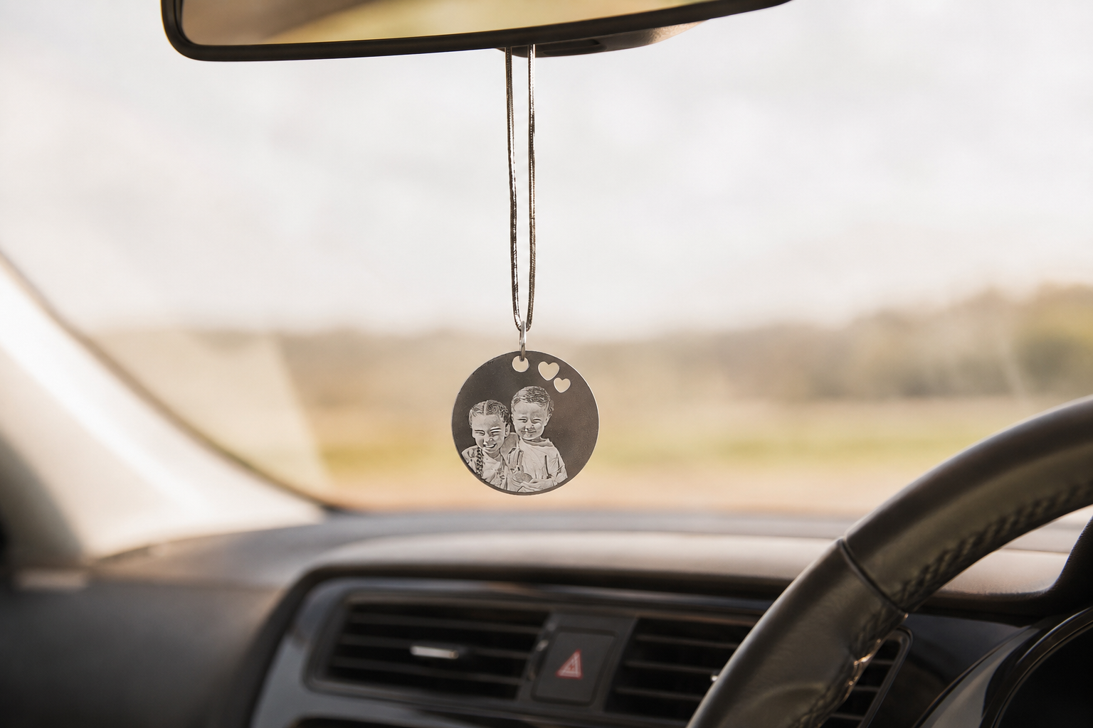 a custom photo pendant hanging in a car rear view mirror
