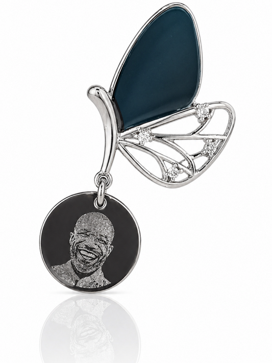 Butterfly-shaped pendant with a circular disc featuring a engraved face on a white background